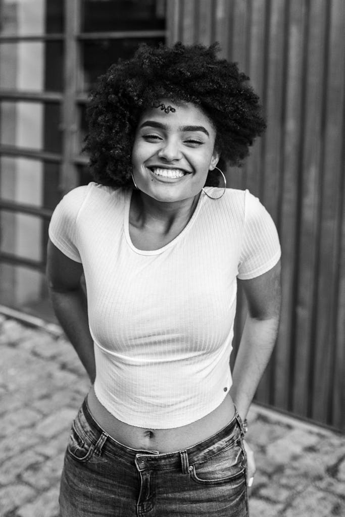 Black and white portrait of a smiling woman outdoors showcasing joy and style.